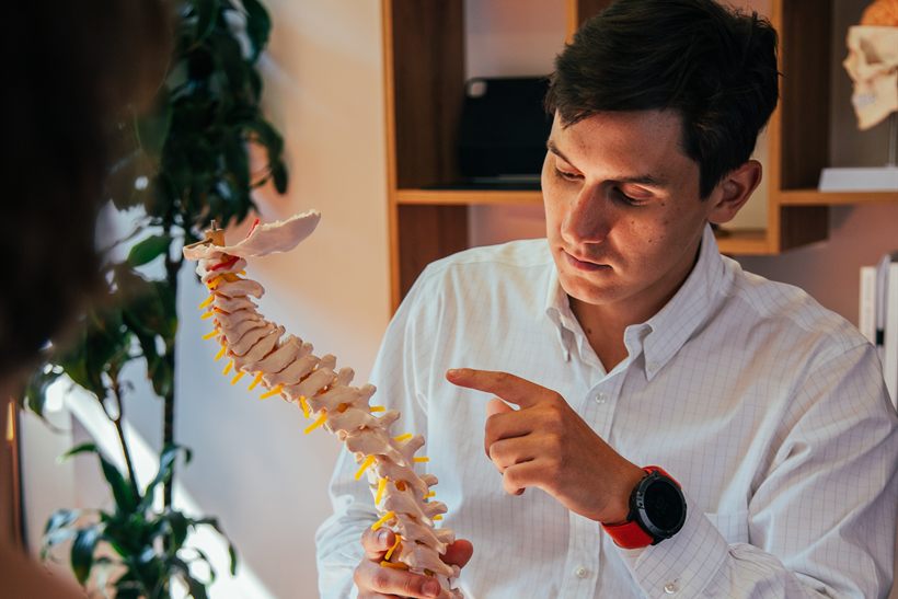 Il Dr. Terrein indica una vertebra su un modello della colonna mentre spiega